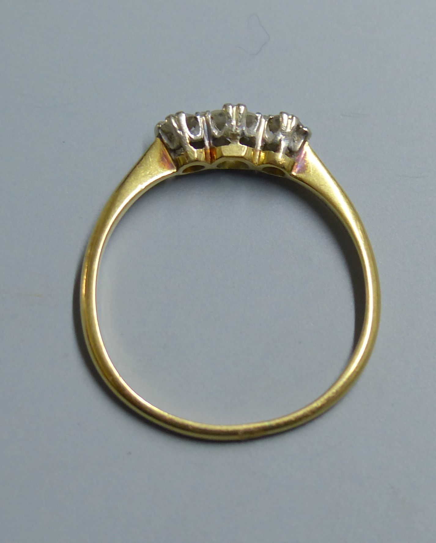 A yellow metal (tests as 18ct) and three stone diamond ring, size O, gross 2.2 grams.